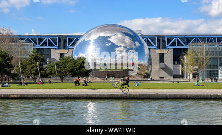 PARIS, Frankreich, 19. MÄRZ 2019: Leute genießen das sonnige Frühling im Parc de la Villette. Ein Mann führt einen Wheelie Trick mit seinem Fahrrad. Stockfoto