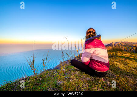 Frau sitzt auf einem Felsen zum Meer suchen, Gabicce Monte, Pesaro und Urbino, Italien Stockfoto