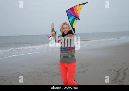 Frau, die in die Richtung der Kamera am Strand mit einem lenkdrachen Stockfoto