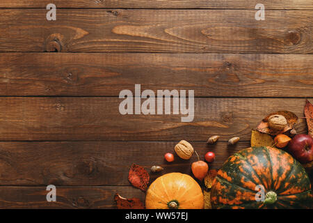 Ernte oder Thanksgiving Hintergrund mit Kürbissen, getrocknet Herbstlaub, Äpfel, rote Beeren, Walnüsse auf hölzernen Tisch. Flach Zusammensetzung, Ansicht von oben, cop Stockfoto