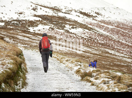 Ein Wanderer und ihrem Hund gehen bis einem Schnee Bowscale fiel im Lake District. Stockfoto