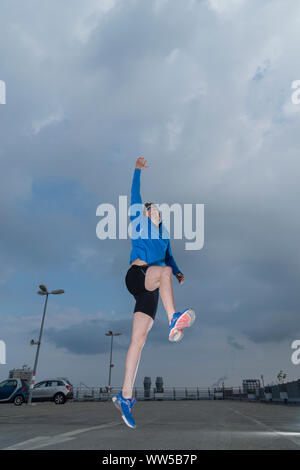 Mann in blauem Trainingsanzug top, Springen, Arm nach oben Stockfoto