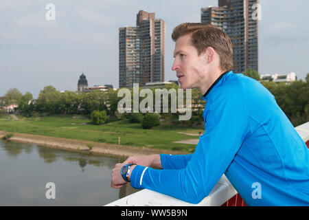 Mann in blauem Trainingsanzug top stehend an Balustrade, auf Entfernung Stockfoto