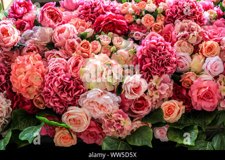Künstliche bunte verschiedene Blumen Hintergrund. Muster der Rosen mit grünen Blättern, schöne bunte Blumen Textur Stockfoto
