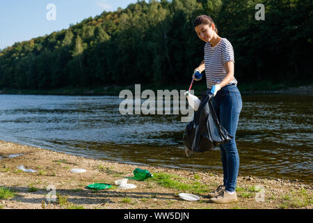 Freiwillige Frau herauf plastik Müll am Strand. Reinigung Umwelt Konzept Stockfoto