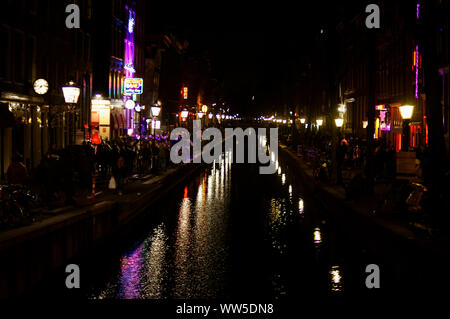Touristen, Laternen und Rot Neon Lichter werden auf der Oberfläche von einem Kanal im Rotlichtviertel von Amsterdam widerspiegeln, Stockfoto