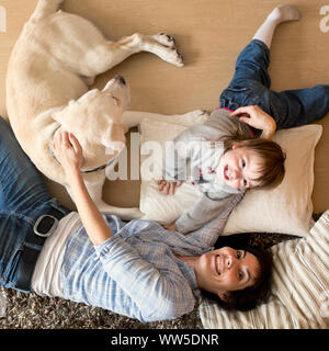 Mutter mit Kind und Hund liegend auf dem Boden, von oben Stockfoto