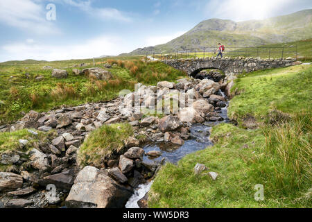 Ein Wanderer Kreuzung Torver Brücke nahe Coniston an einem sonnigen Sommertag im englischen Lake District. Stockfoto