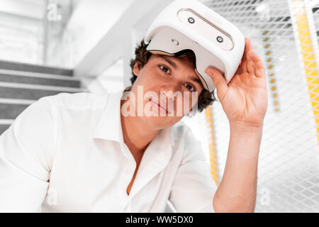 Nahaufnahme der lächelnden attraktiver Mann mit Virtual reality Brillen mit zeitgenössischen hellen Co-Working Büro. Der VR-Erfahrung. Stockfoto