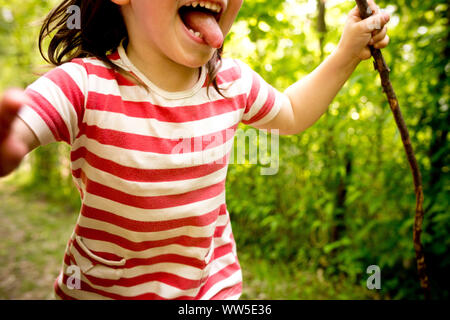 4-6 Jahre altes Kind mit gestreiftem Hemd und Stick in der Hand läuft durch den Wald, Nahaufnahme, detail, Stockfoto