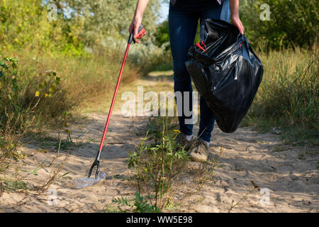 Freiwillige Frau herauf plastik Müll im Wald. Reinigung Umwelt Konzept Stockfoto