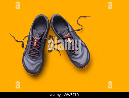 Ansicht von oben grau und orange Trainer auf gelbem Hintergrund. Stockfoto