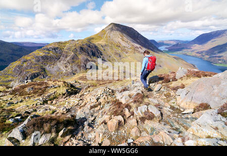 Eine weibliche Wanderer und ihrem Hund absteigend Ein steiniger Weg vom Gipfel des Hay Stacks im englischen Lake District. Stockfoto