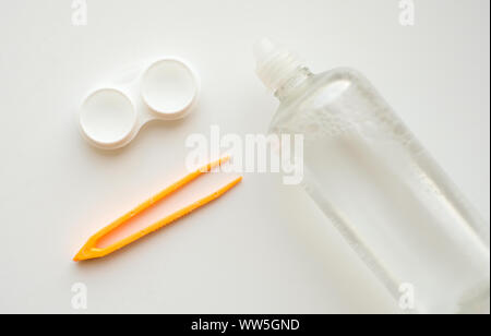 Zubehör für die richtige Verwendung von Kontaktlinsen: Gehäuse, Pinzette und Flasche Lösung auf weißem Hintergrund. Sichere Sehkorrektur. Blick von oben. Stockfoto