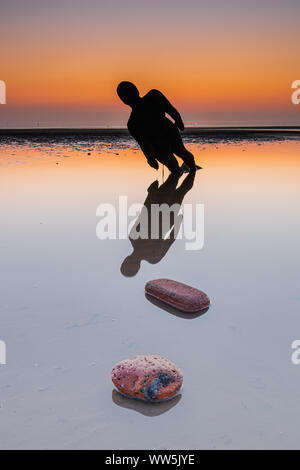 Antony Gormley Gusseisen Statuen, Bestandteil der Installation benannt "Woanders", am Strand von Crosby in Sefton bei Sonnenuntergang. Stockfoto