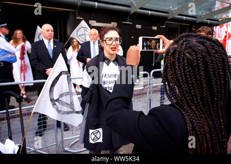 London, Großbritannien. 13 Sep, 2019. Aussterben Rebellion Aktivisten in weißen Kleidern und 'blutenden Herzen' selbst bis zum Haupteingang der London Fashion Week Messe geklebt. Andere Mitglieder des Aussterbens Rebellion gegossen Eimer von gefälschten Blut um den Eingang und führte eine 'die-in", fordert, dass die Modeindustrie die Wahrheit über seinen Beitrag zum Klima- und ökologische Krise Kredit zu sagen: Gareth Morris/Alamy leben Nachrichten Stockfoto