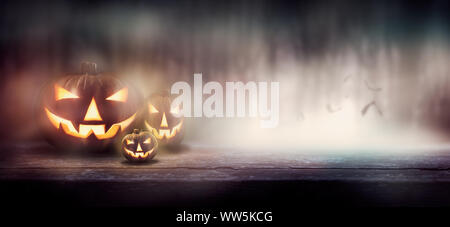 Die bösen leuchtenden Augen von Jack O'Lanterns durch Dunst und Nebel in einem Wald auf einer Halloween Nacht. Stockfoto