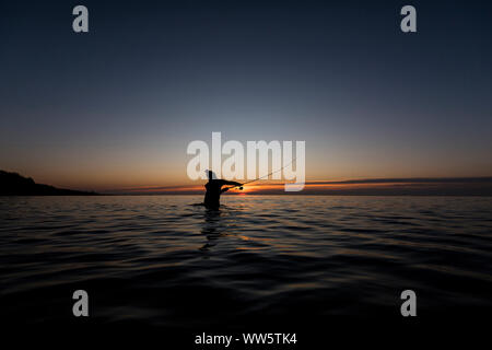 Angler Angeln in der Ostsee bei Sonnenuntergang in Wasser. Stockfoto