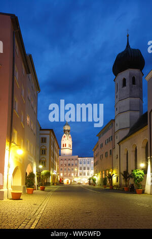 Stadt Pfarrkirche St. Nikolaus auf dem Max-Josefs-Platz links, Heiligen Geist Kirche auf der rechten Seite, Heiliger Geist Straße, historische Wohnhäuser und Gewerbebauten in der Dämmerung, Rosenheim, Oberbayern, Bayern, Deutschland, Europa Stockfoto