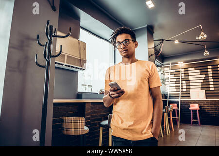 Der Mensch mit seinem Smartphone in einem Coffee Shop. Das Konzept der Studie, freiberuflich, arbeiten. Moderne Einrichtung. Stockfoto