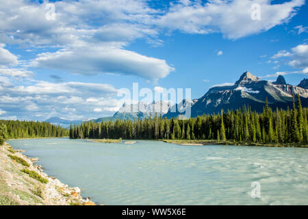 Kanada, Rocky Mountains, Fluss mit Bäumen gesäumten Ufer, Berge im Hintergrund Stockfoto