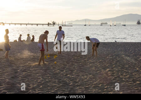 Männer spielen mit einem Ball am Strand, Containerschiffe in den Horizont, English Bay, Vancouver Stockfoto