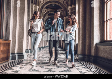 Youngs und wunderschön. Zuversichtlich sind eine Gruppe von Studenten zu Fuß in der Hochschule, Plaudern und lächelnd. Stockfoto