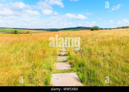 Ein gepflasterter Fußweg Kurven über die Derbyshire Landschaft auf einem hellen Anfang September Tag. Stockfoto