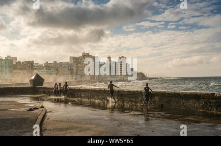 Kinder warten auf die nächste Welle schlagen über den Malecon in Havanna, Kuba Stockfoto