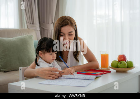 Asiatische Mutter spielt mit ihren Toddler zusammen mit Buntstifte am Tisch im Wohnzimmer zu Hause. Stockfoto