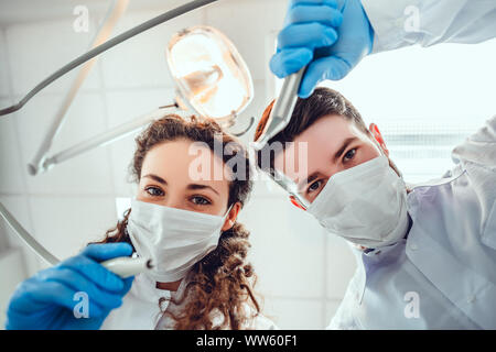 Low Angle Portrait von männlichen und weiblichen Zahnärzte tragen Masken an der Zahnklinik. Stockfoto