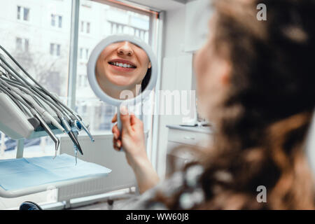 Schöne junge Frau im Spiegel mit Smile in Zahnarzt s Büro. Stockfoto