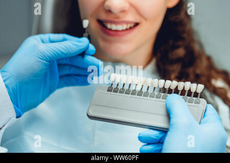 Zahnarzt auswählen Patienten Zähne Farbe mit Palette in der Klinik, bis Anzeigen schließen. Stockfoto