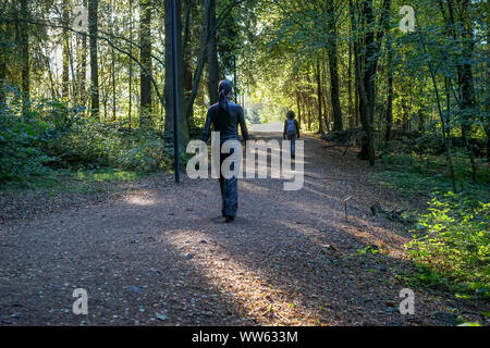 Die Skulptur 'Frau' des Künstlers Sean Henry auf der Spur im Herbst in der Ekebergparken Sculpture Park. Unbekannte Mädchen ist in der Ferne Stockfoto