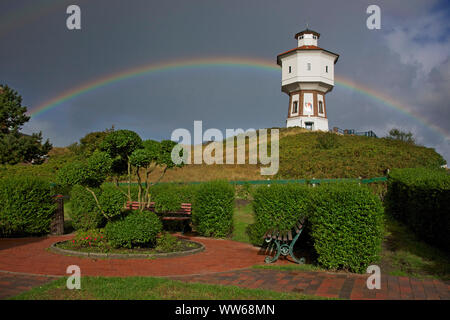 Blick von einem kleinen Park auf einem Regenbogen hinter dem alten Wasserturm, dem Wahrzeichen der Insel Langeoog.