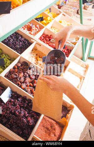 Die Frau ist die Verpackung getrocknet aprisots im Lebensmittelgeschäft. Getrocknete Früchte in die Holzkisten, veganes Essen Stockfoto