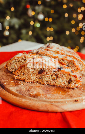 Christstollen. Traditionelle süße Früchte Brot mit Puderzucker bestreuen. Weihnachten Urlaub Tabelle mit Stollen. Weihnachtsbaum im Zimmer auf dem Hintergrund Stockfoto