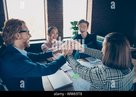 Vier schön chic elegante stilvolle Fröhliche positive froh Geschäft Haie Experten sammeln Termin setzen die Hände über Desktop auf eine moderne industrielle Stockfoto