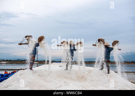 Drei Salz Bauern stehen auf einem Haufen von Salz, Vietnam Stockfoto