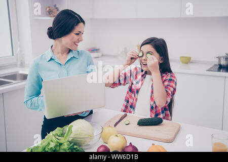 Porträt von zwei schön süß Schöne attraktive Sweet adorable fröhliche Menschen Mädchen täuschen schließen die Augen mit frische Gurke Stücke in Licht Stockfoto