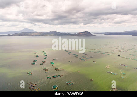 Lake Taal mit einem Vulkan und Fisch Käfigen auf eine Fischzucht, Ansicht von oben. Luzon, Philippinen tropischen Landschaft, Berge und Vulkan in den See. Stockfoto