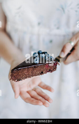 Frau mit einer Scheibe der Blaubeere Chocolate Brownie Kuchen Stockfoto