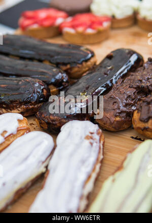Hintergrund mit bunten Kuchen und Desserts gefüllt. Verschiedene verschiedenen mini Kuchen mit Sahne, Schokolade und Beeren. Stockfoto