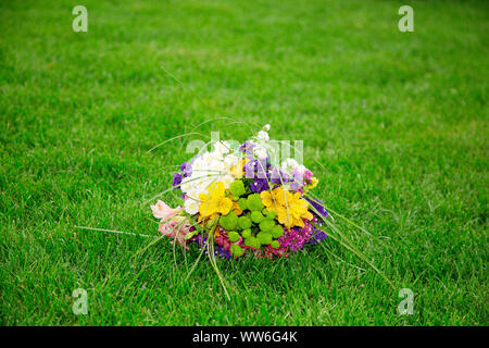 Brides Bouquet von bunten Blumen liegen auf einem grünen Rasen. Wedding Bouquet. Bündel von verschiedenen bunten Blumen liegen auf einem Hintergrund von grünem Gras. W Stockfoto
