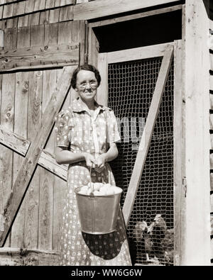 1930er Jahre lächelnde Frau Tragen von Brillen AUF KAMERA HOLDING EIMER MIT frisch gelegte Eier STEHEN AN DER TÜR ZU CHICKEN COOP-p2820 HAR 001 HARS DAMEN PERSONEN, DIE VEREINIGTEN STAATEN VON AMERIKA LANDWIRTSCHAFT VERTRAUEN BRILLEN LANDWIRTSCHAFT B&W NORDAMERIKA AUGENKONTAKT BRUNETTE NORDAMERIKANISCHEN GLÜCK FRÖHLICHE EIMER AUSSEN LANDWIRTE COOP STOLZ BERUFEN LÄCHELT VERBINDUNG HÜHNER FRÖHLICH FRISCH MITTE NACH MITTE DER ERWACHSENEN FRAU GEFLÜGEL SCHWARZ UND WEISS KAUKASISCHEN ETHNIE HAR 001 FESTGELEGTEN ALTMODISCH Stockfoto