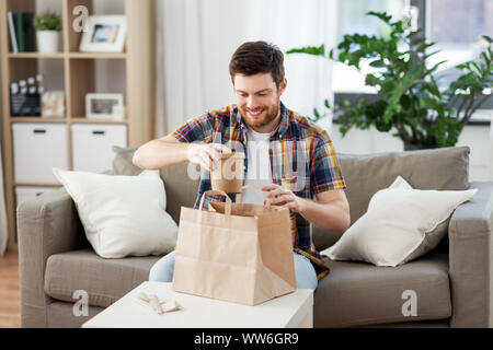 Lächelnd Mann auspacken Essen zum Mitnehmen zu Hause Stockfoto