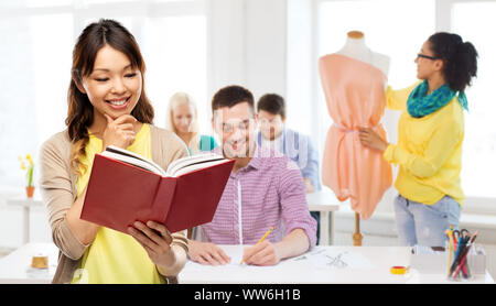 Asiatische Frau mit Buch über Mode Design Studio Stockfoto