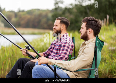 Männliche Freunde mit Angeln auf dem See Stockfoto