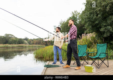 Männliche Freunde mit Angeln am See Pier Stockfoto