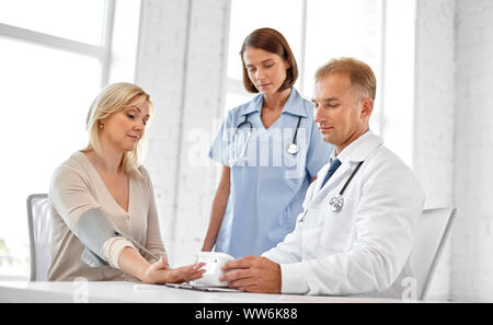 Arzt Messung des Patienten Frau Blutdruck Stockfoto